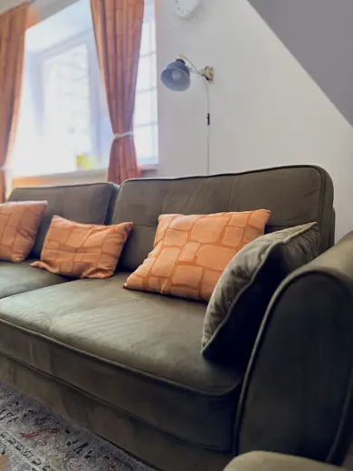 Sofa w ciemnym odcieniu z pomarańczowymi poduszkami