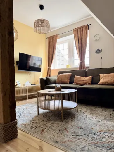 Salon z żółtą ścianą, sofa i telewizor.