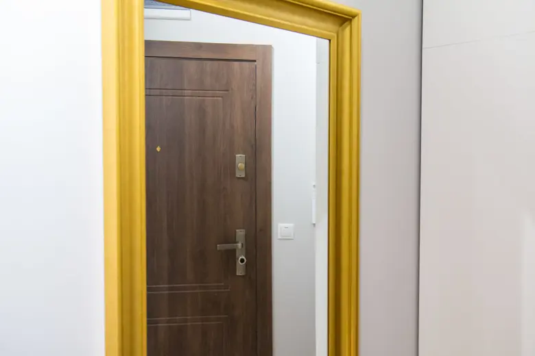 Wejście do mieszkania z ciemnymi drzwiami i żółtą ramą.