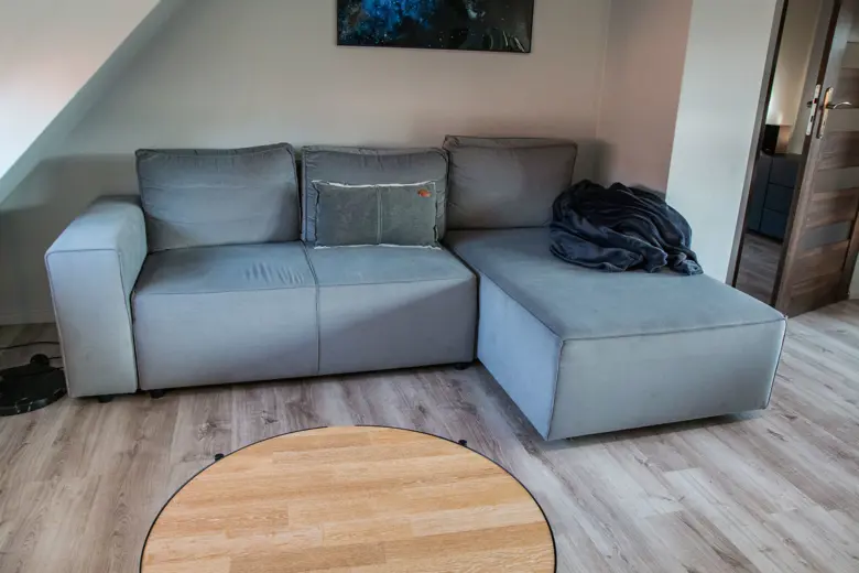 Szara sofa narożna z częścią chaise i okrągłym stolikiem