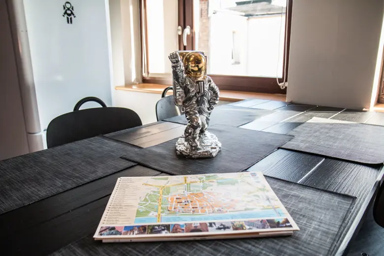 Stół jadalny z mapą i metalową rzeźbą astronauty w rogu.