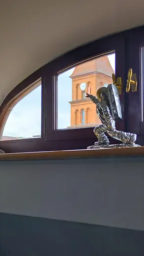 Okno o łukowatym kształcie z figurką na parapecie.