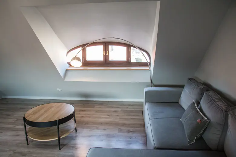 Sofa przy łukowym oknie, okrągły stolik i lampka