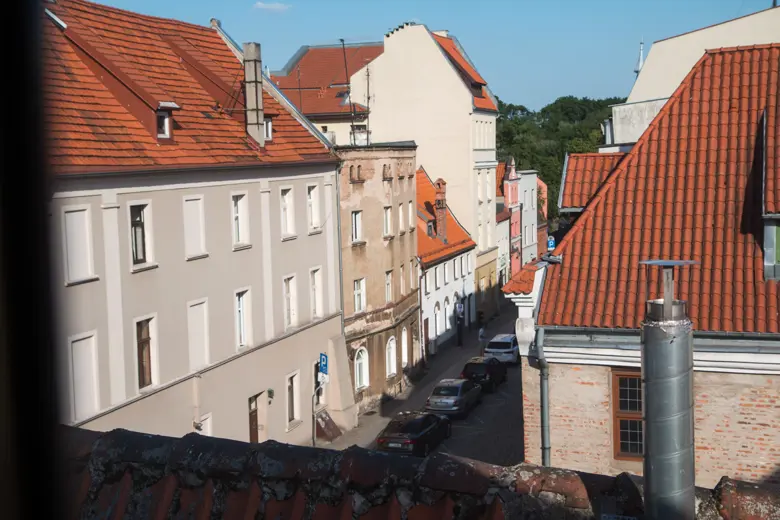 Widok na sąsiednie kamienice i czerwone dachy.