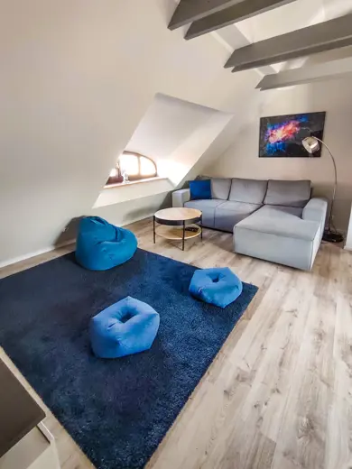 Szara sofa w kształcie L z okrągłym stolikiem i błękitnymi poduszkami