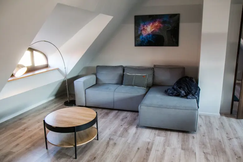 Sofa narożna w jasnym wnętrzu, obraz nad sofą i okno