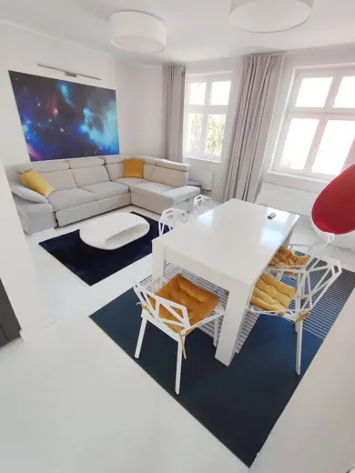 Salon z sofą narożną, kosmicznym obrazem i dużymi oknami