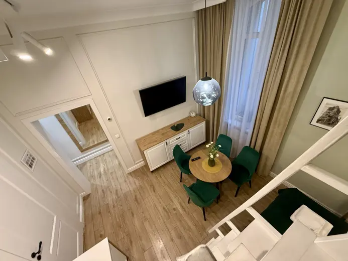 Salon z wygodnym narożnikiem, TV i stołem jadalnym.