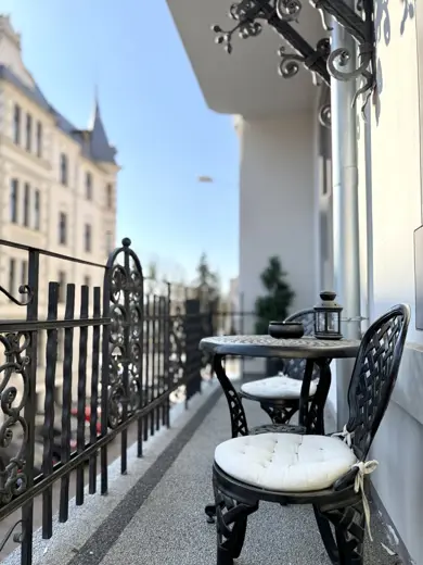 Balkon z metalowym balustradą, stolik i dwa krzesła.