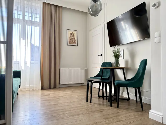 Przestronny salon z telewizorem na ścianie i stolikiem.