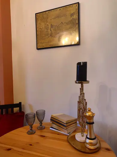 Stół z dekoracjami, świecznikiem, książkami i mapą na ścianie.