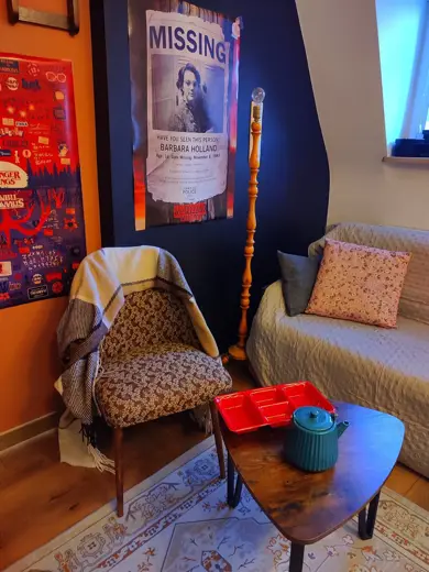 Klimatyczny kącik z krzesłem w wzorzystej tapicerce i plakatem Missing na ścianie