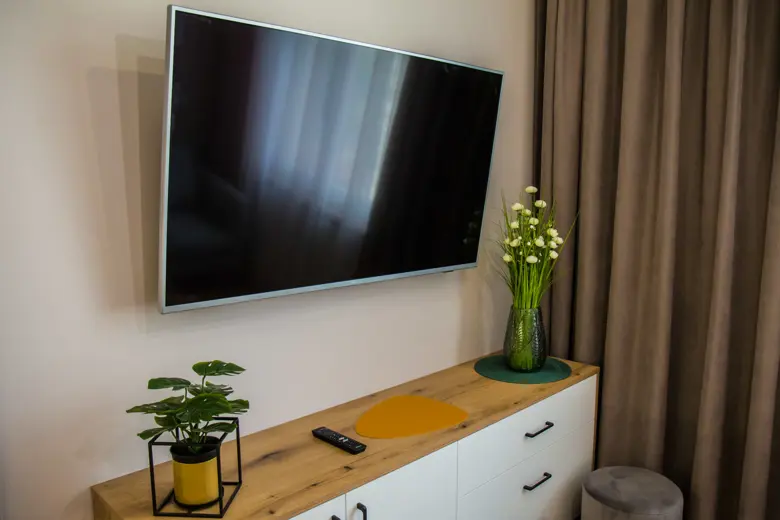 Telewizor na ścianie z zasłonami i dekoracją