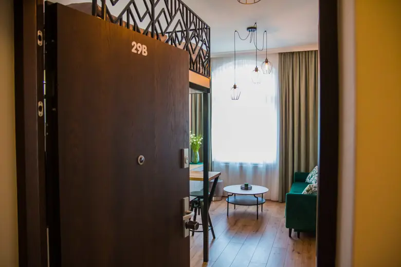 Salon z zieloną sofą, dużym oknem i stolikiem kawowym