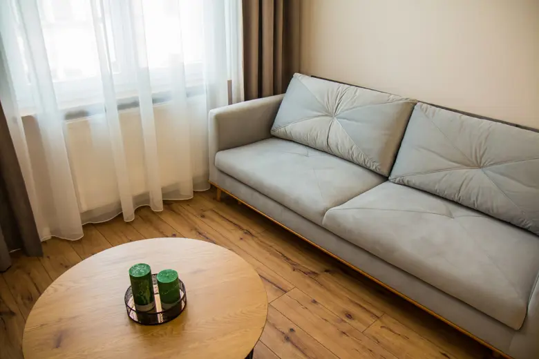 Dwa zielone świeczniki w metalowej tacy na stoliku.