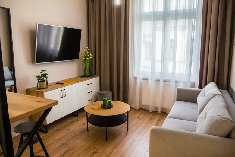 Salon z telewizorem na białej szafce i zasłonami
