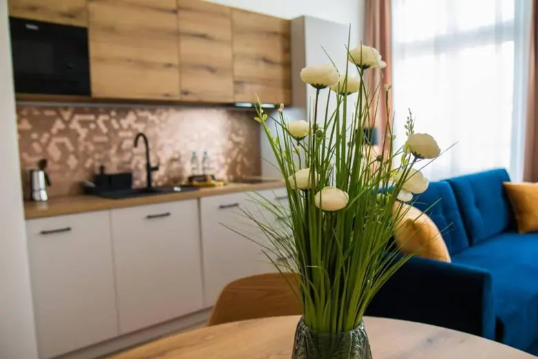 Kuchnia z rośliną w doniczce na tle okna i kwiatowymi akcentami