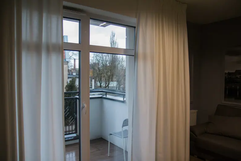 Duże okno balkonowe z zasłonami i balkonem