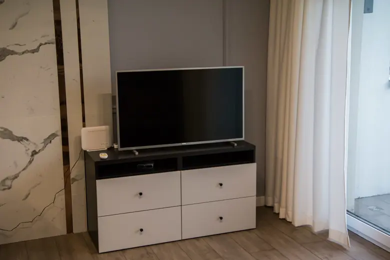 Telewizor na białej szafce z szufladami