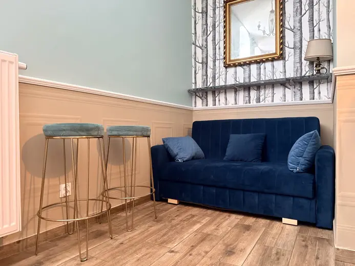 Niebieska sofa przy tapetach z motywem drzew